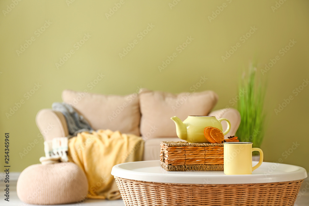 Teapot and cup of hot beverage on table in room