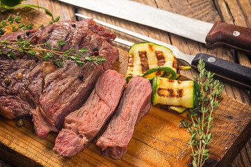 Sticker - Juicy medium rare beef steak slices on wooden board with herbs spices and salt.