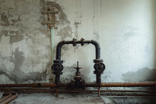 Old Water Pipes Against Abandoned Wall