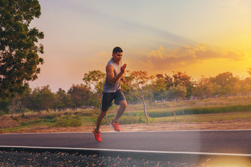 Wall Mural - Silhouette of man running sprinting on road. Fit male fitness runner during outdoor workout with sunset background