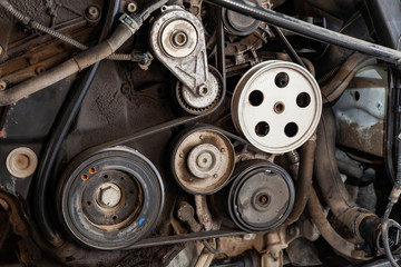 Poster - Close up shot of the pulley system and drive belt on a powerful diesel or gasoline used engine with parts of the car and vehicles with dirty oil on them