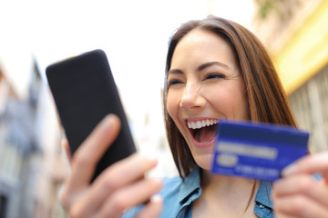 Wall Mural - Excited woman paying online with credit card and cellphone