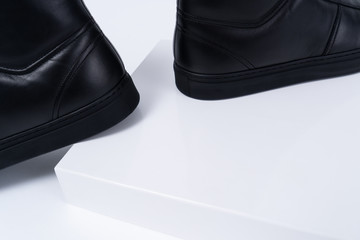 Two black leather boots on white background. Closeup on shoe box and footwear. Copy space.