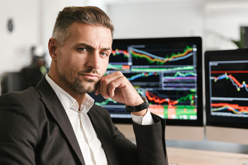 Fototapete - Image of successful businessman working in office on computer with graphics and charts at screen