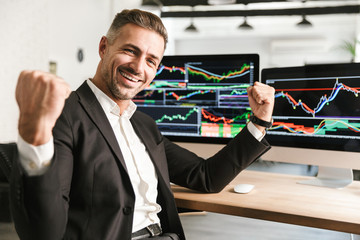 Fototapete - Image of joyful businessman working in office on computer with graphics and charts