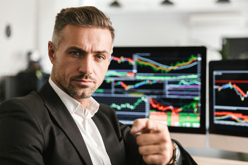 Fototapete - Image of businesslike man working in office on computer with graphics and charts at screen