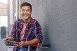 © mavoimages - Happy young man leaning on his bicycle using a tablet