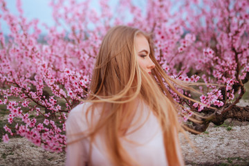portrait of young lovely blonde woman in spring pink pastel flowers