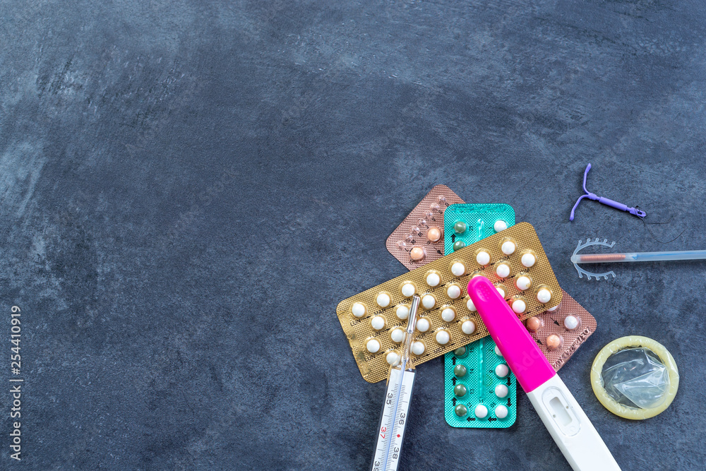 Choosing method of contraception : Birth control pills, an injection syringe, condom, IUD-method, on grey - obrazy, fototapety, plakaty 
