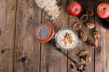 Wall Mural - light healthy breakfast  with yogurt on oatmeal muesli and walnuts in a glas on a rustic wooden table. close up