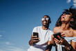 © karrastock - Two happy friends using the mobile in the street. Friendship concept.