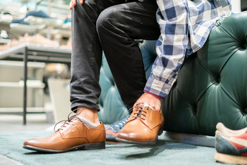 elegant businessman try on new brown classic shoes