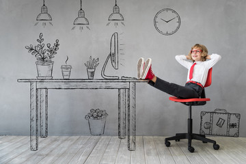 Wall Mural - Happy child sitting at the desk in imaginary office