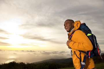 Wall Mural - happy young african american man with backpack walking in mountains