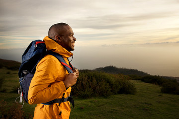 side of happy male backpacker walking outdoors in nature