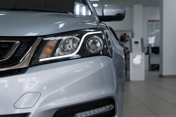 Closeup headlights of a modern car. Detail on the front light of a car. Modern and expensive car concept. The car is in the showroom