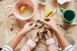 © Seventyfour - Above view closeup of mature woman and little child shaping clay in pottery workshop for family, copy space