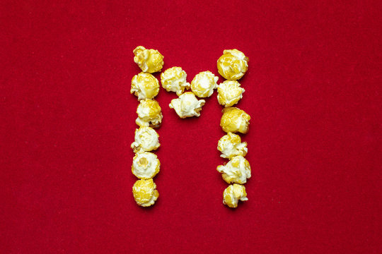 English alphabet from cinema popcorn. Letter M. Red background for design. Movie styling.