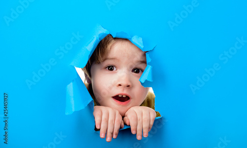 Fotografía Surprised child boy looking through hole paper