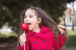© nellas - Adorable little girl eating red apple covered with sugar icing