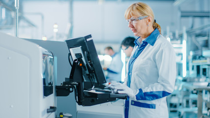 On High Tech Factory Female Engineer Uses Green Screen Computer for Programing Pick and Place Electronic Machinery for Printed Circuit Board Surface Mount Assembly Line. 