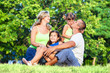 © Avatar_023 - Happy family with two daughters sitting on the grass in park