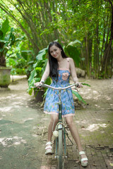 Asian pretty girl has biking a bicycle with happy and smiling at Little Tree Garden cafe, Nakhon Pathom province, Thailand in the morning.