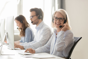 Wall Mural - happy mature female call center agent looking at camera smiling