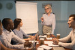 © fizkes - Smiling old coach giving presentation on flipchart training young employees