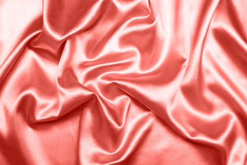 Close up of ripples on silk fabric. Satin textile background. Living Coral color. Top view. Color of the year 2019.