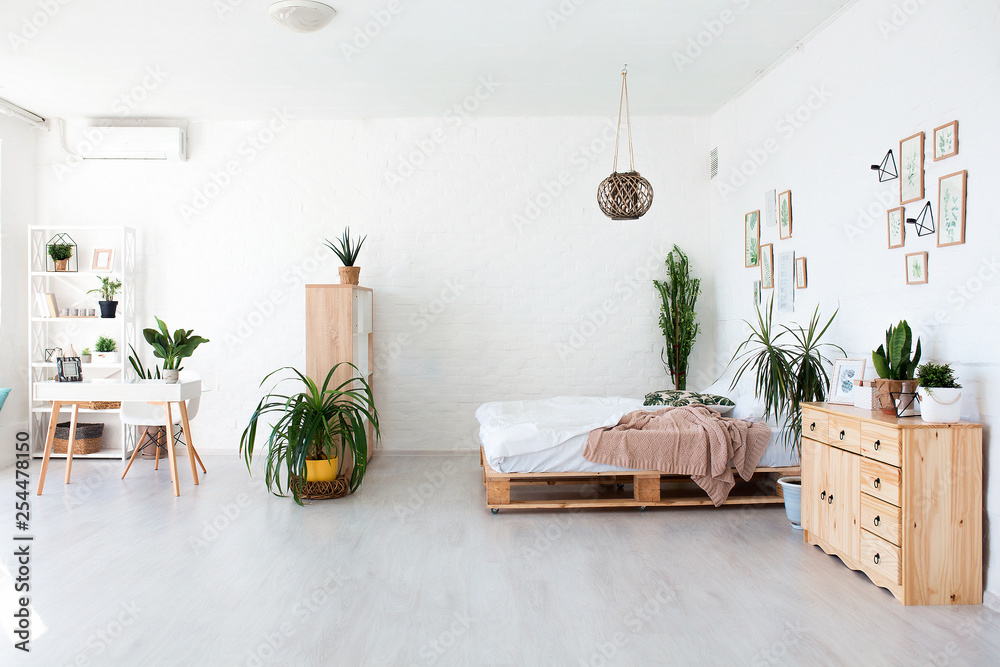 Cozy interior design of modern studio apartment in Scandinavian style. A spacious huge room in light colors with wooden bed and stylish expensive luxury furniture. - obrazy, fototapety, plakaty 