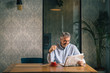 © cherryandbees - senior man reading newspaper and drinking coffee in cafeteria