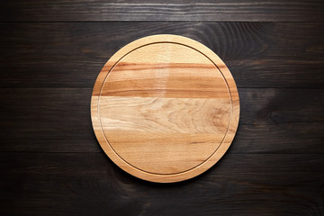 Wall Mural - Round cutting board on brown wooden table. Top view