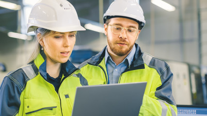 Poster - Male and Female Industrial Engineers Work on a Manufacturing Plant, They Discuss Project, Point in the Direction of the Machinery while Using Laptop. 
