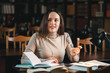 © proimagecontent - Pensive brunette student girl thinking about her exams while studying at the library