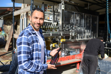 Wall Mural - young man wine maker working filling wine bottle with automatic bottling machine