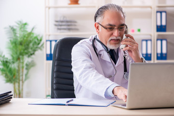 Wall Mural - Aged male doctor working in the clinic 