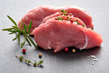 Close-up on slices of raw beef meat. Tenderloin with herbs and spices on stone board.