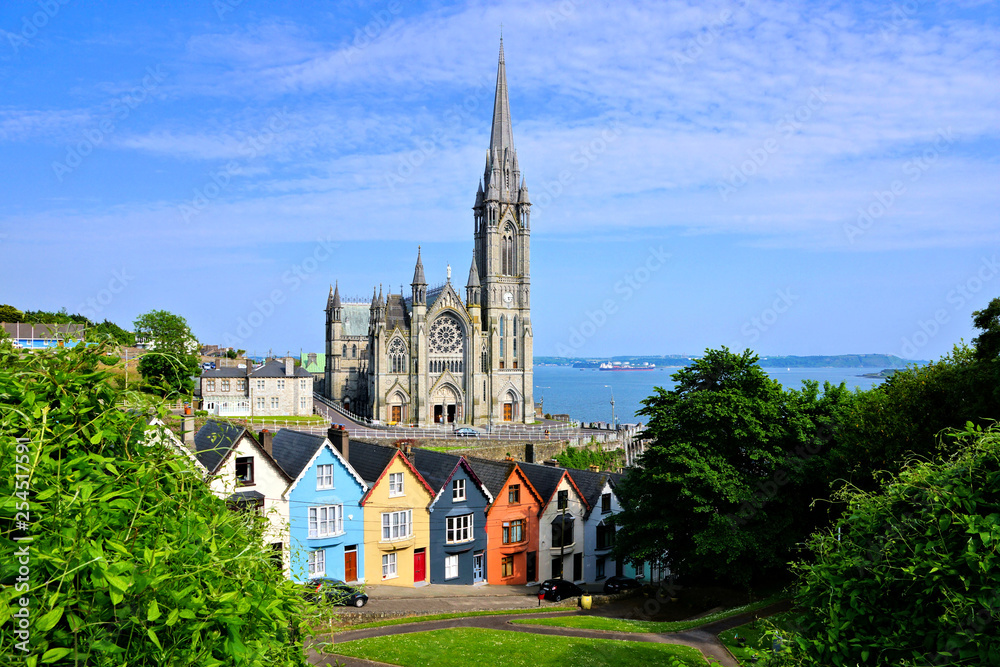 Colorful row houses with towering cathedral in background in the port town of Cobh, County Cork, Ireland - obrazy, fototapety, plakaty 