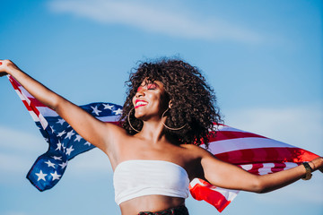 Black woman with afro hair and an american flag celebrating the independence day of USA