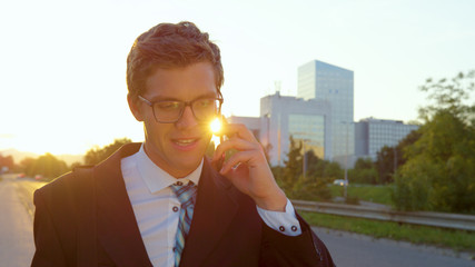 Wall Mural - LENS FLARE Golden sunbeams shine on yuppie talking on the phone while going home