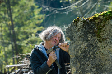 Wall Mural - Senior sculptor with curly hair carving in stone