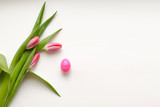 Fototapeta Tulipany - Bouquet of pink three tulips with green leaves with one egg on a white background. Beautiful flower in the spring season. Top view of empty space