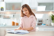 © New Africa - Cute little girl reading book at table in kitchen
