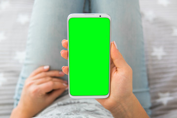 Wall Mural - chroma key Green screen smartphone top view Mockup image of woman's hands holding mobile phone.