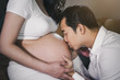 Husband kissing to his wife's belly