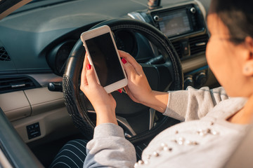 Woman driver using smart phone in car during traffic jam , blank screen for design purpose .