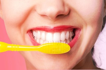 Wall Mural - Female brushing teeth with yellow brush, close up