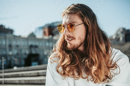 Fotomural Handsome young man with long curly hair spending time outdoors