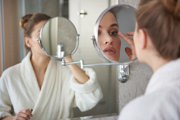 Young lady retouching her eyelashes make up